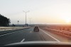 Passenger car driving on highway at dawn in front